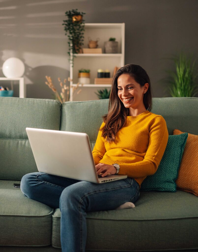 Smiling woman building her business website on a laptop at home
