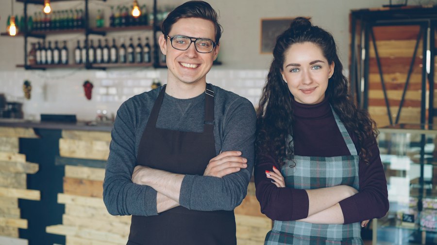 Two café owners standing proudly in their coffee shop
