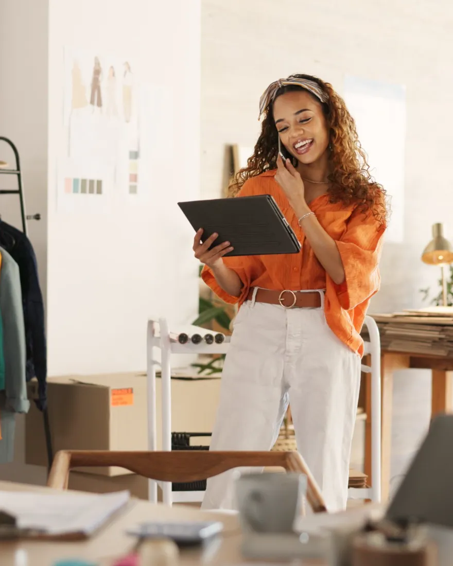 Smiling small business owner checking online orders on a tablet in her clothing studio